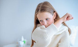 Girl coughing into her arm