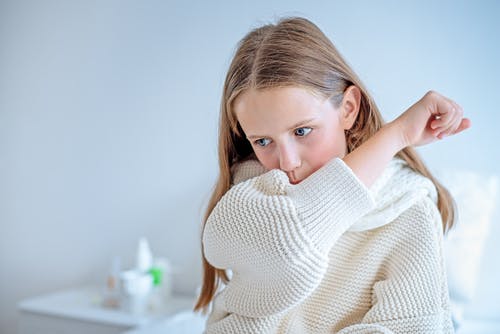 Girl coughing into her arm