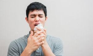 Image of man coughing into a tissue