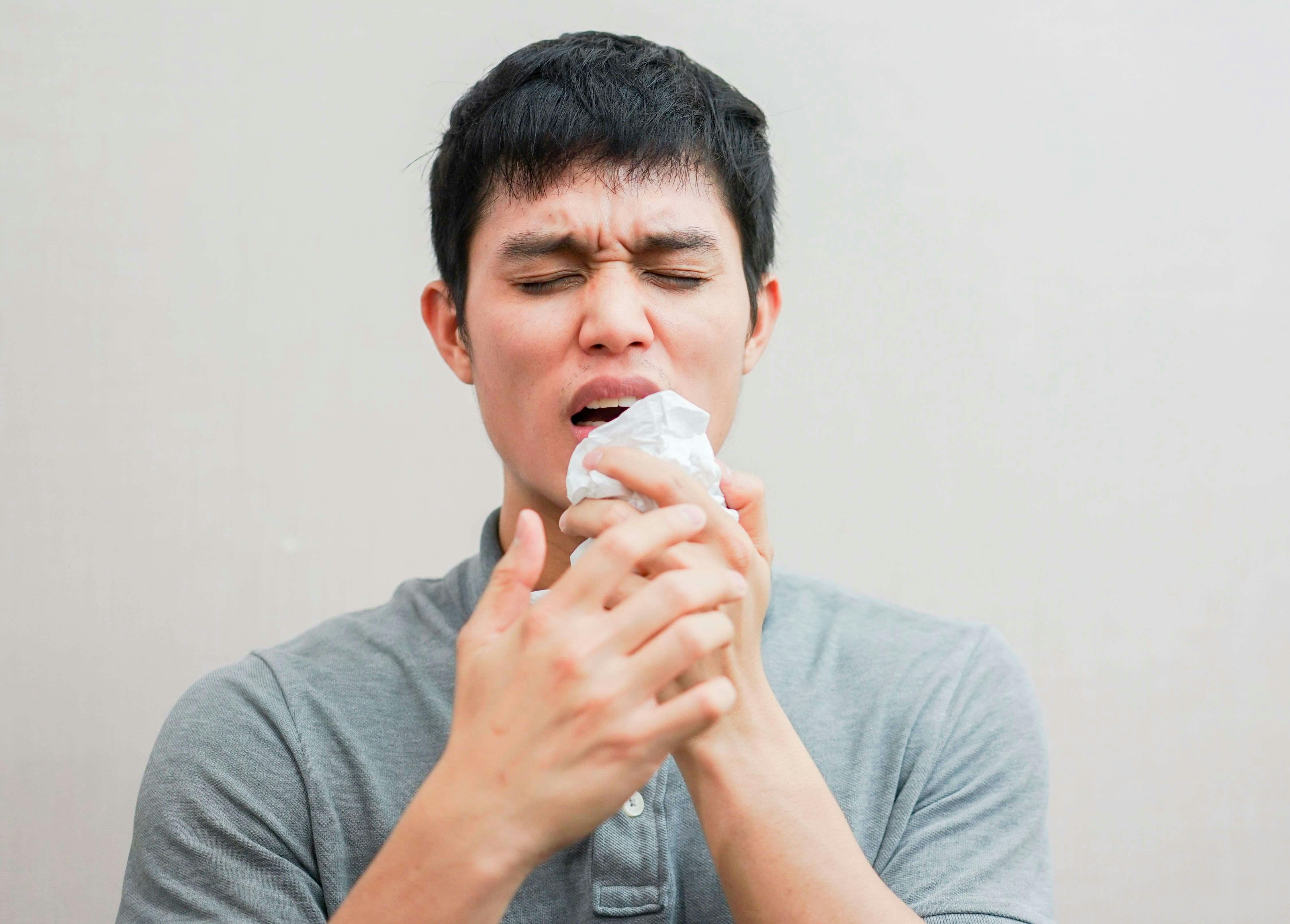 Image of man coughing into a tissue