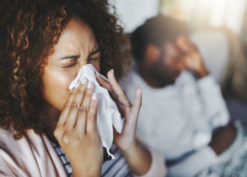 Woman blows her nose into a tissue