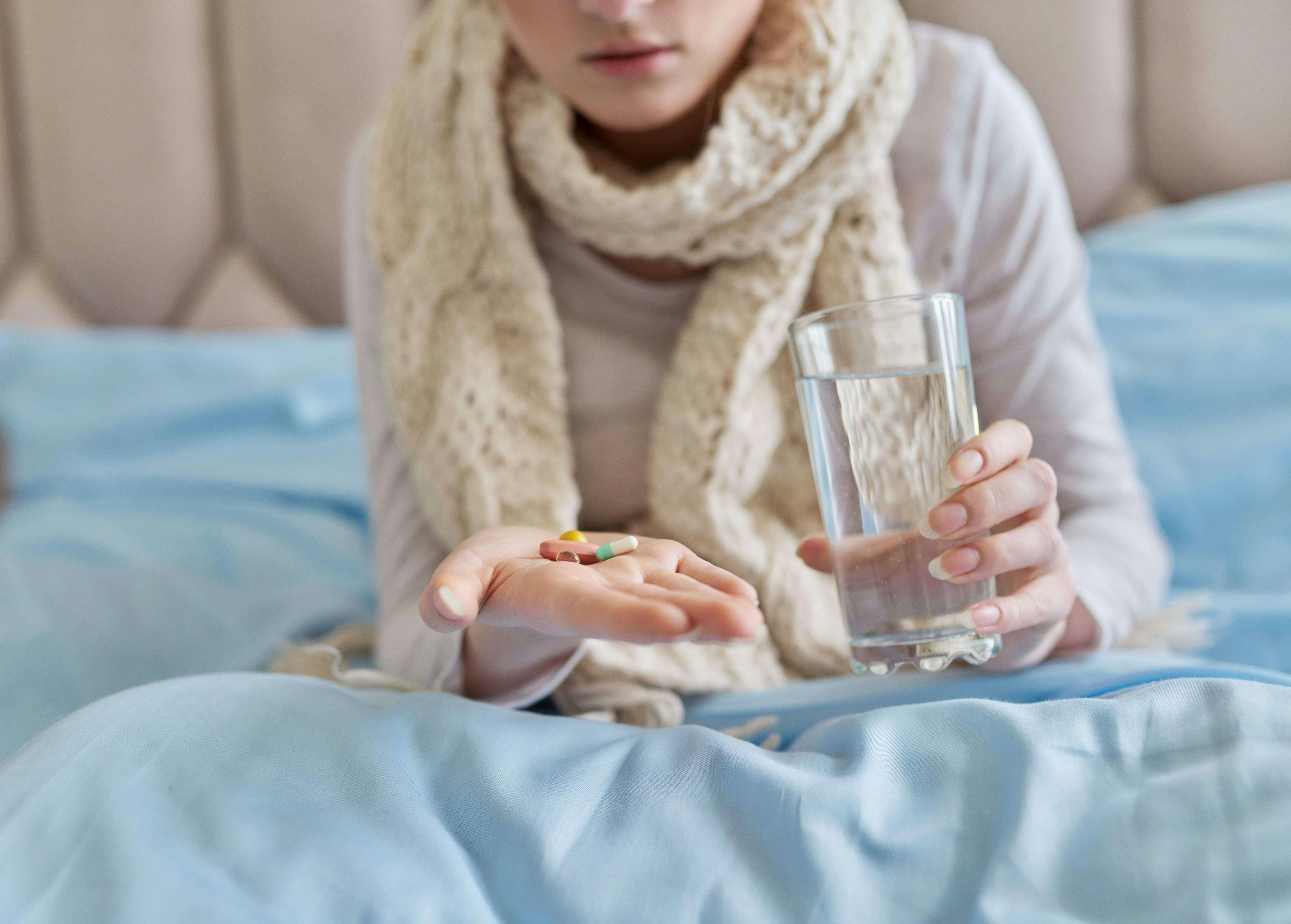 A woman in bed holding pills