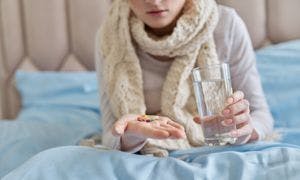 A woman in bed holding pills