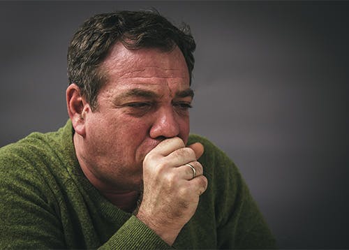 Man in the middle of a dry coughing fit has a red face