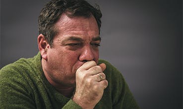 Man in the middle of a dry coughing fit has a red face