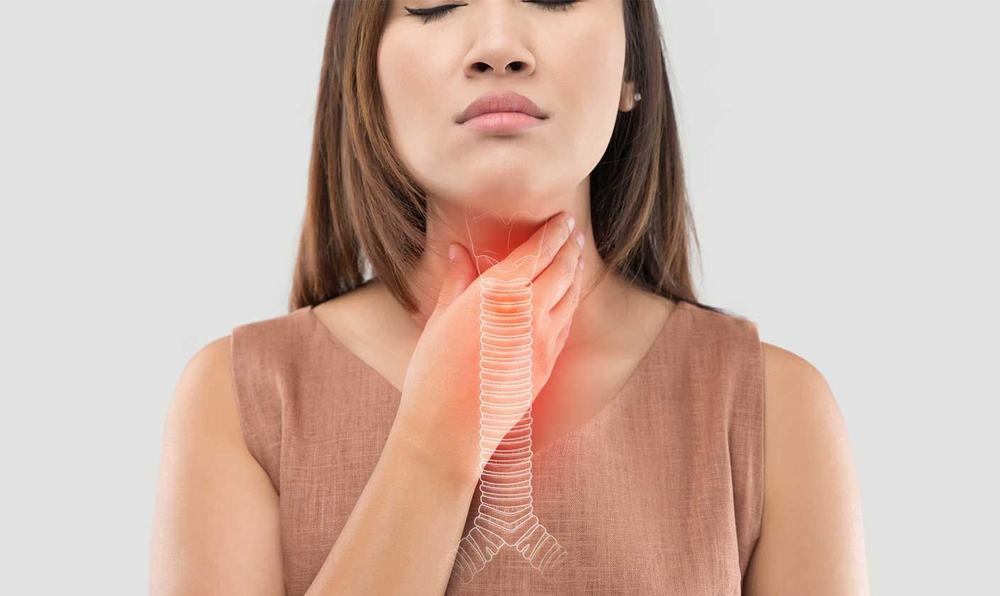 Woman holding her throat with 3-D image of trachea and bronchial tubes.