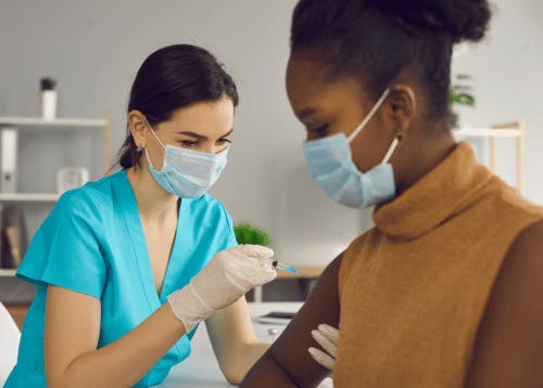 Medical professional in a face mask giving a vaccine to a patient