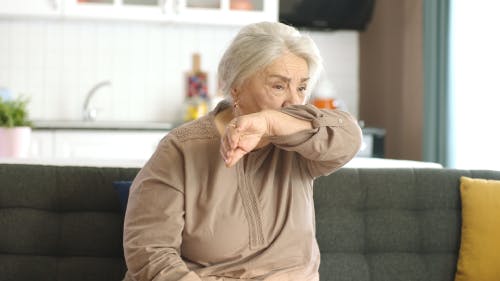Woman coughing into her arm  