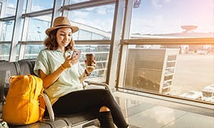 Woman sitting in an airport with her travel bags.