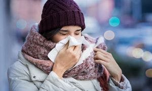 Young woman dressed for winter weather and blowing her nose