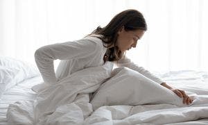 Woman with body aches sitting up in bed