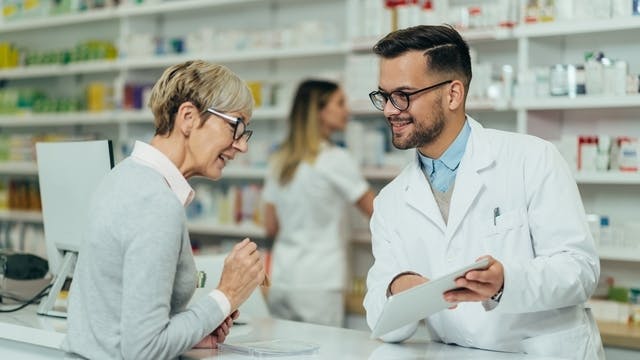 Woman speaking to man at pharmacy counter