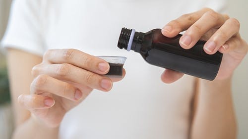 Woman pouring cough syrup into cup