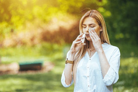 Woman using nasal spray outside Woman using nasal spray outside