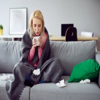 Sick woman sitting on couch with tea