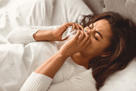 Woman blowing her nose in bed