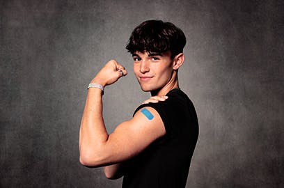 Man flexing his bicep and showing a blue band aid