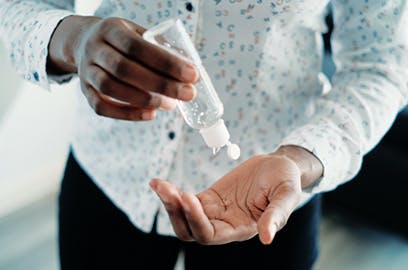 A man is putting hand sanitizer on his hand from a bottle