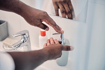 A man’s hand is pumping soap into the other hand to wash their hands