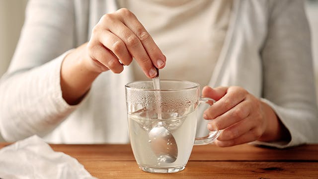 Woman stirring powder into glass of water
