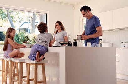 A man and a woman and their 2 children are preparing food together in the kitchen