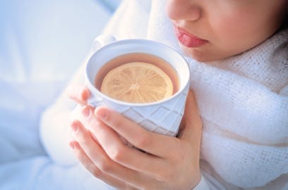 Woman drinking hot tea with lemon