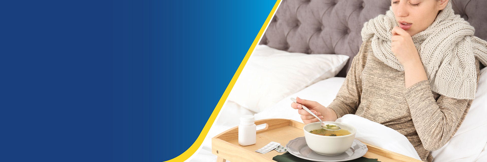 Young sick woman lying in bed eating broth off of a bed tray