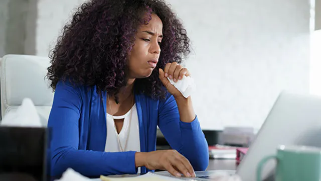 Sick woman working from home at computer 