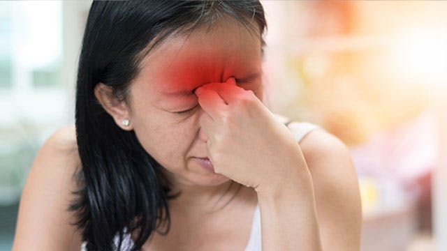 Woman experiencing sinus pressure pinches her nose