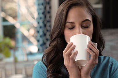 Woman closing her eyes drinking from a mug that she’s holding with two hands