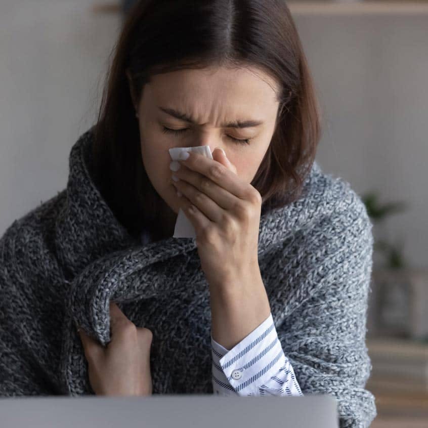 Woman sneezing into tissue