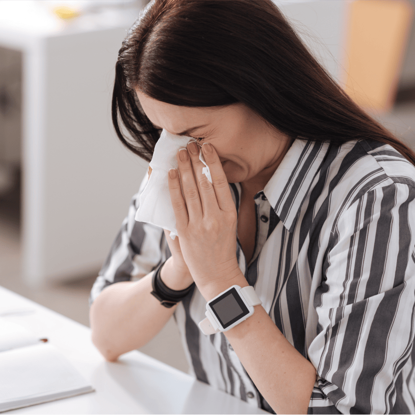 Woman sneezing into tissue