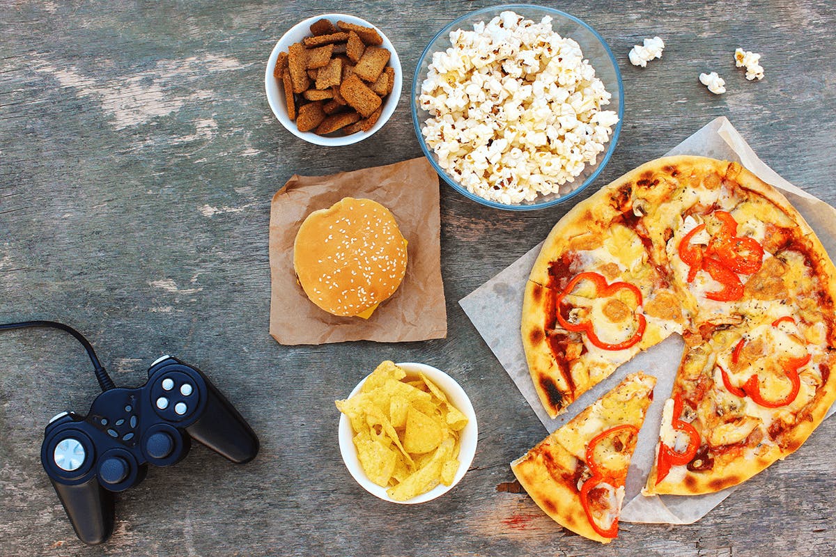 A selection of fast food, pizza, and popcorn near a gaming controller
