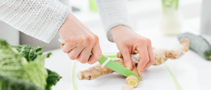 Woman slicing ginger root with a knife