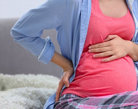 pregnant woman holding stomach and lower back