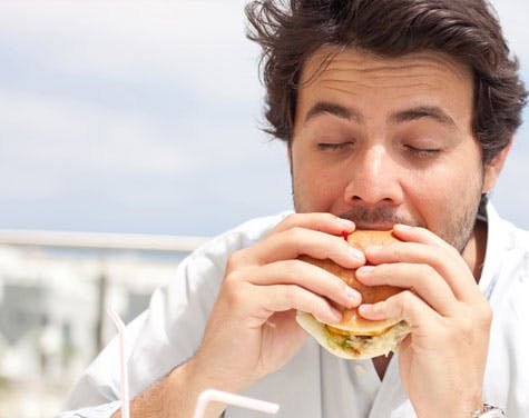 man eating a burger with eyes closed