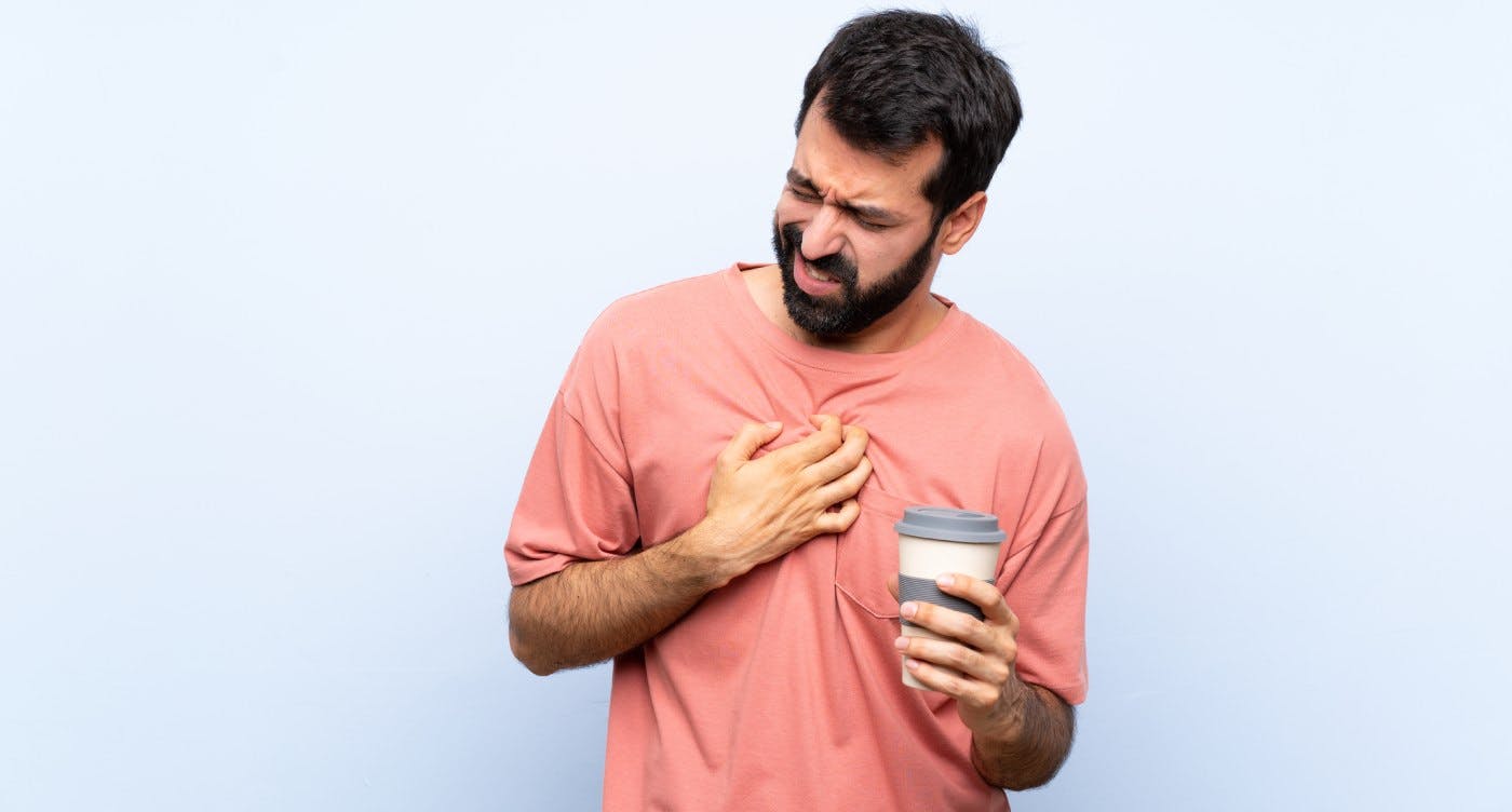 Man holding stomach and holding coffee