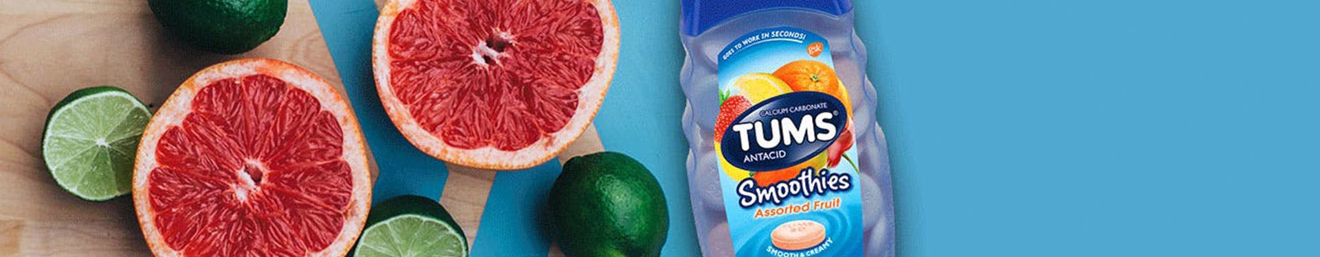 Image of a bottle of TUMS Smoothies Product along with cut oranges and limes