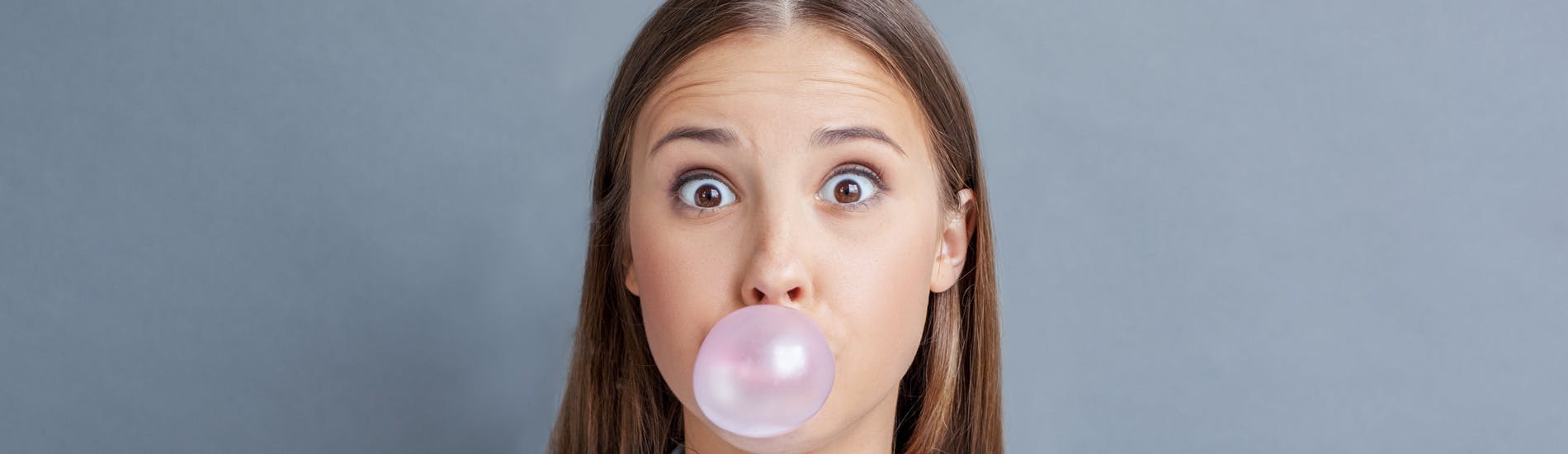 woman chewing gum against a gray background