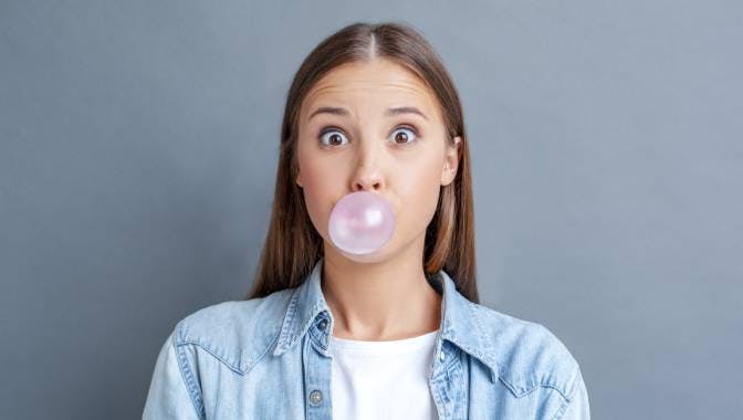 woman chewing gum against a gray background