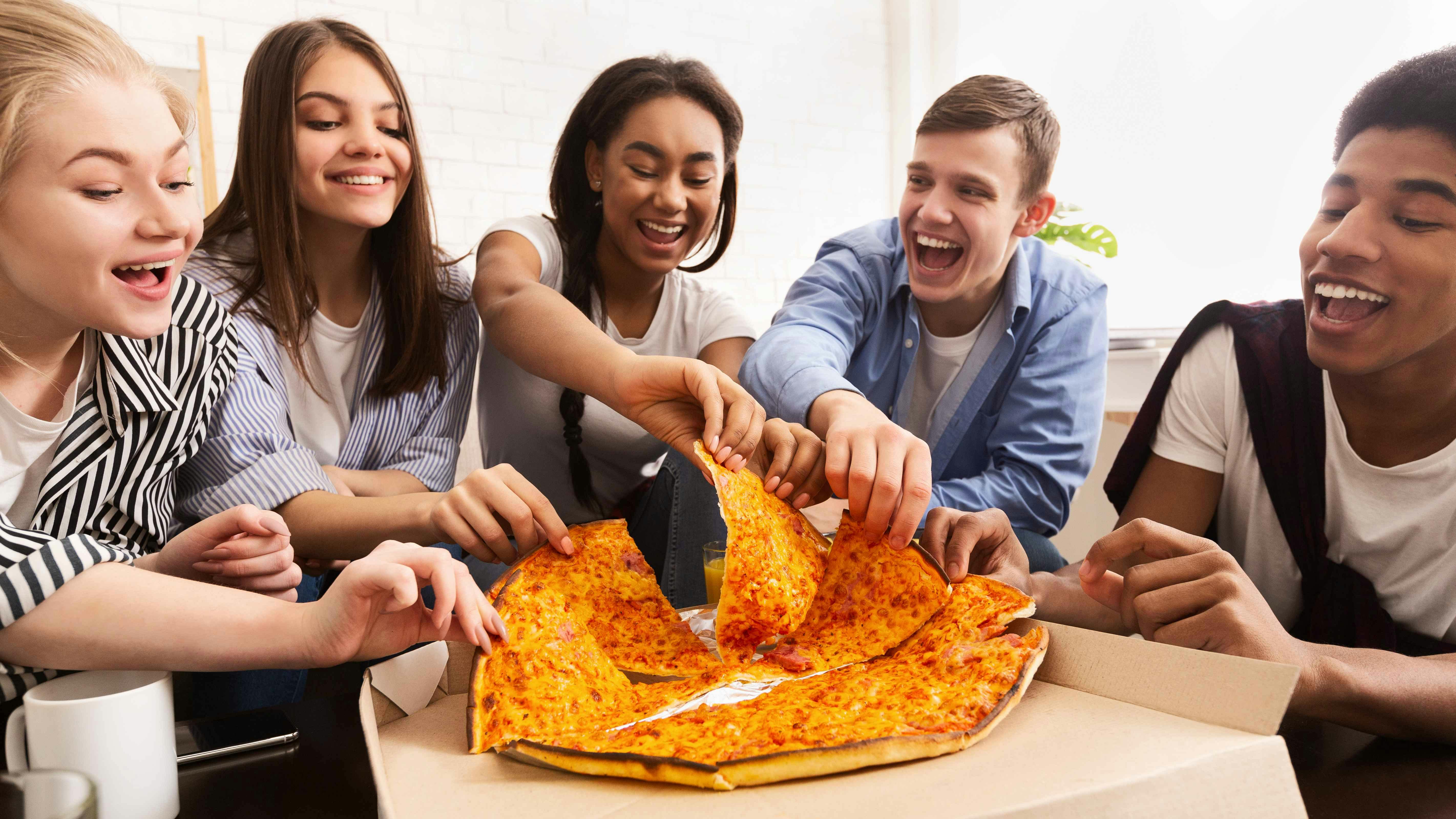 A group of teens eating pizza together