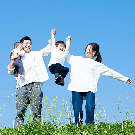 子供と手をつないで持ち上げる両親 