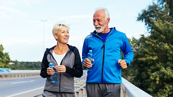 Older couple walking down a road to exercise Older couple walking down a road to exercise