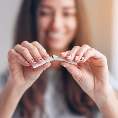 Young woman breaking cigarette in half.