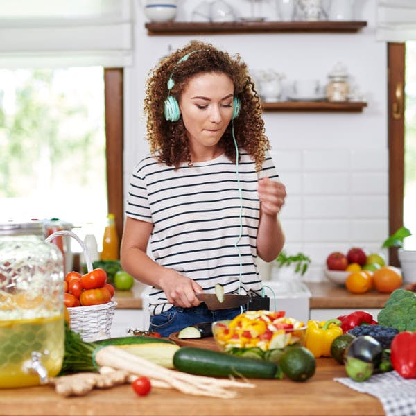 Happy woman cooking while listening to music.