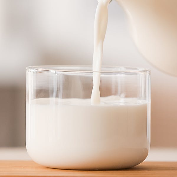 A jug pouring milk into a glass.