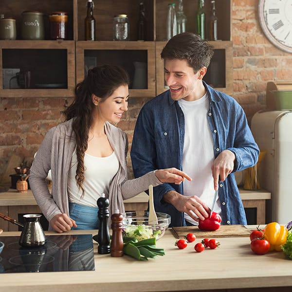 Couple cooking food together on purple background 