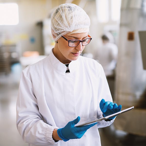 Woman in protective gear checking a clipboard in a lab Woman in protective gear checking a clipboard in a lab