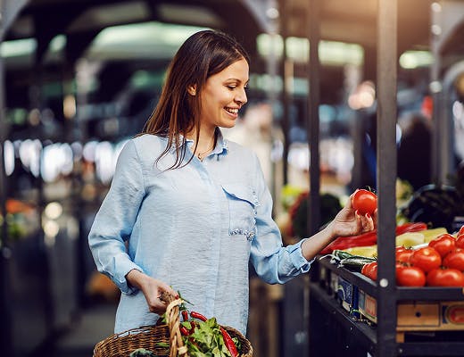 Femme souriante dans un champ avec son panier de récolte Femme souriante dans un champ avec son panier de récolte