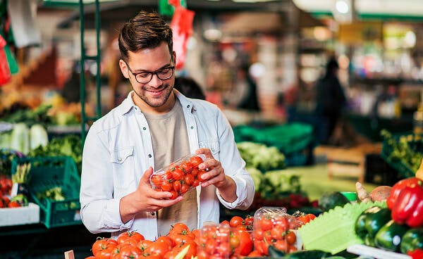 Man at the market happily purchasing tomatoes 